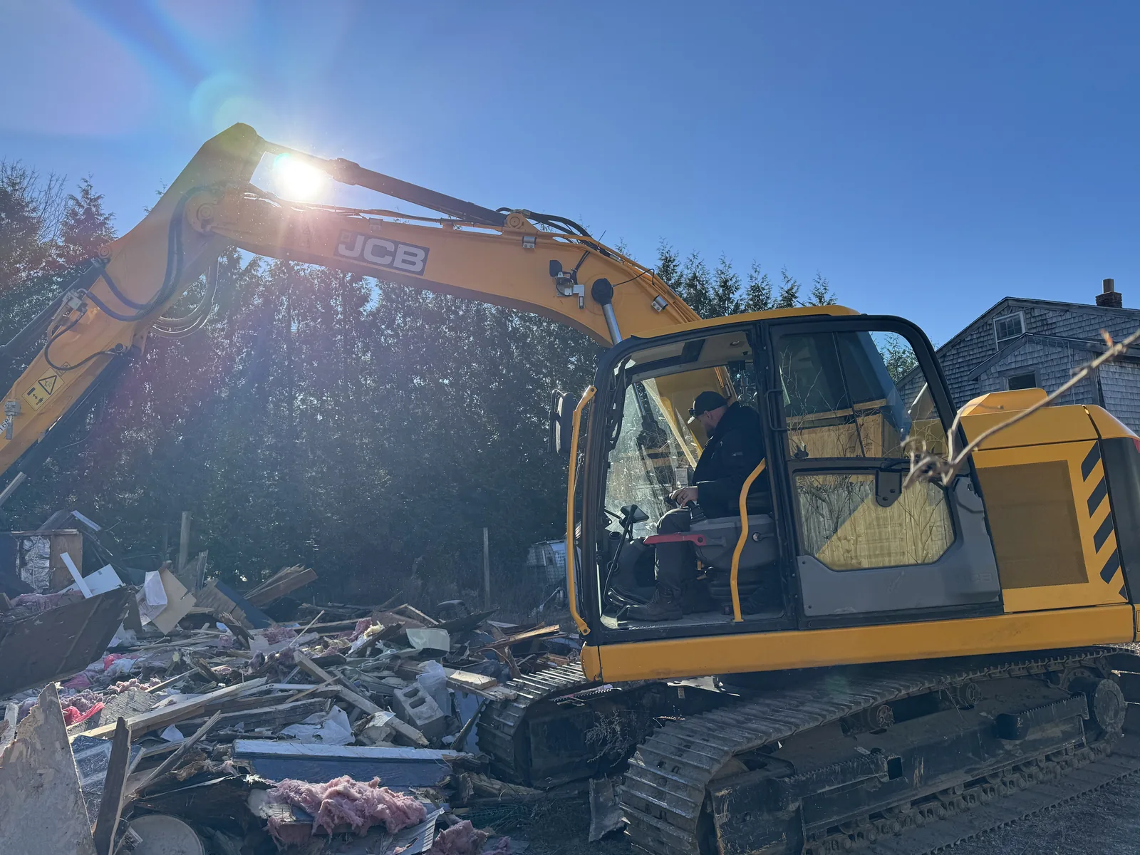 Excavator working in the debris field of a torn down building on a sunny day, building demolition