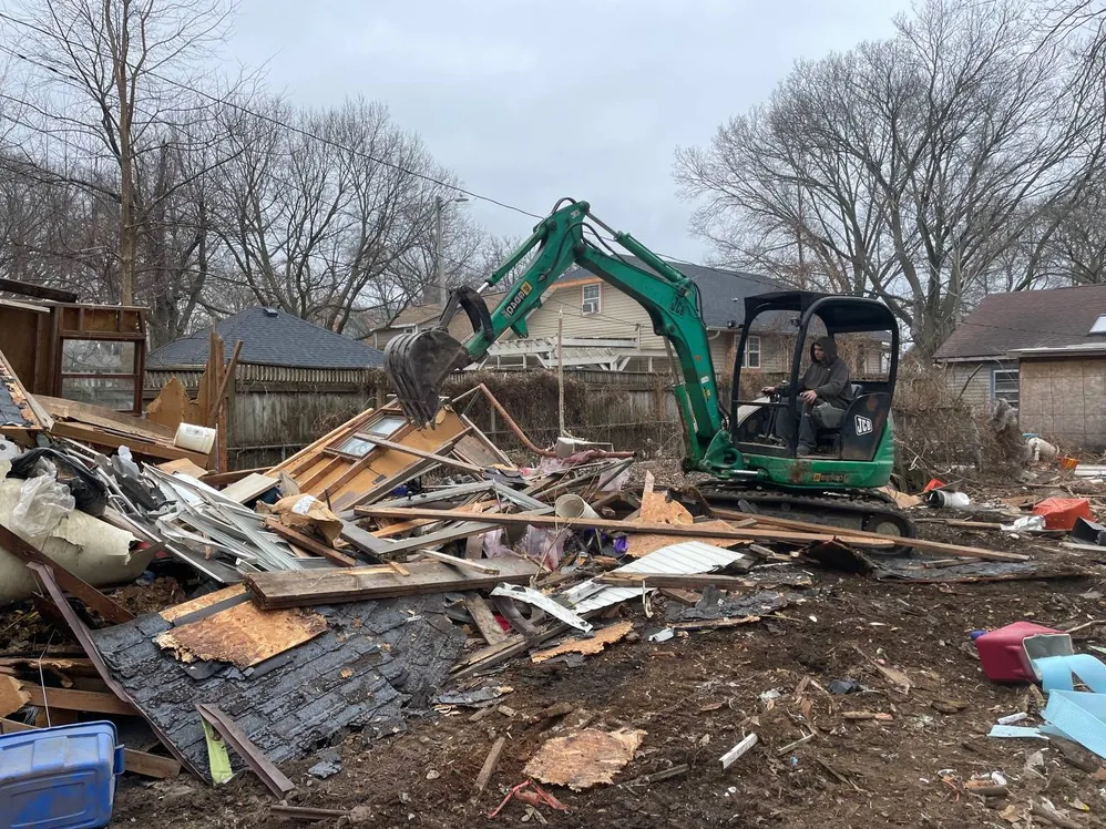 Mini excavator pulling apart the debris of a torn down home, mobile home demolition
